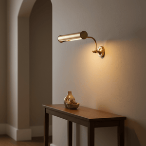 Solid brass wall lamp illuminating a wall above a wooden console table with decorative items.