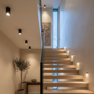 A staircase with wooden steps, black marble downlight holders, a potted plant, and a wall art piece.