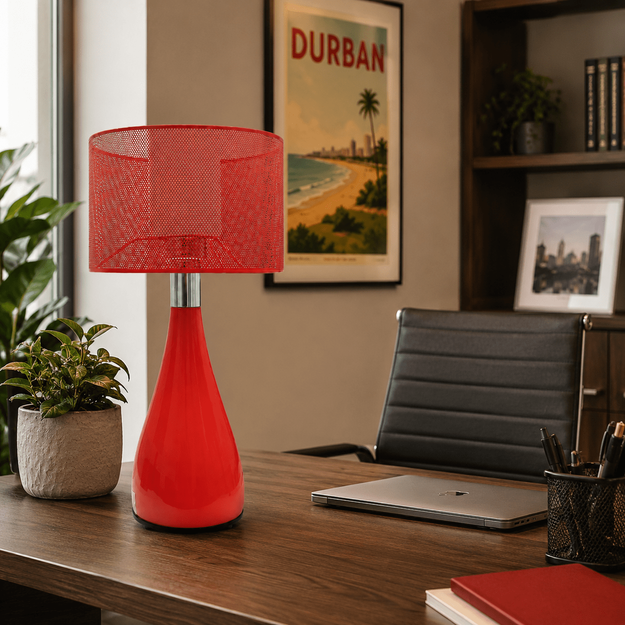 Red lamp on a desk with a laptop, notebook, and office chair in an office setting.