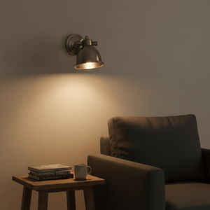 Antique silver wall lamp illuminating a cozy reading nook with a chair and side table.
