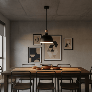 Black metal and wood pendant light hanging above a wooden dining table with bowls, framed art on the wall.