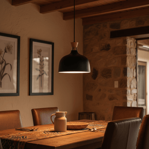Black metal and wood pendant light hanging above a rustic dining table set with a pitcher and woven basket.