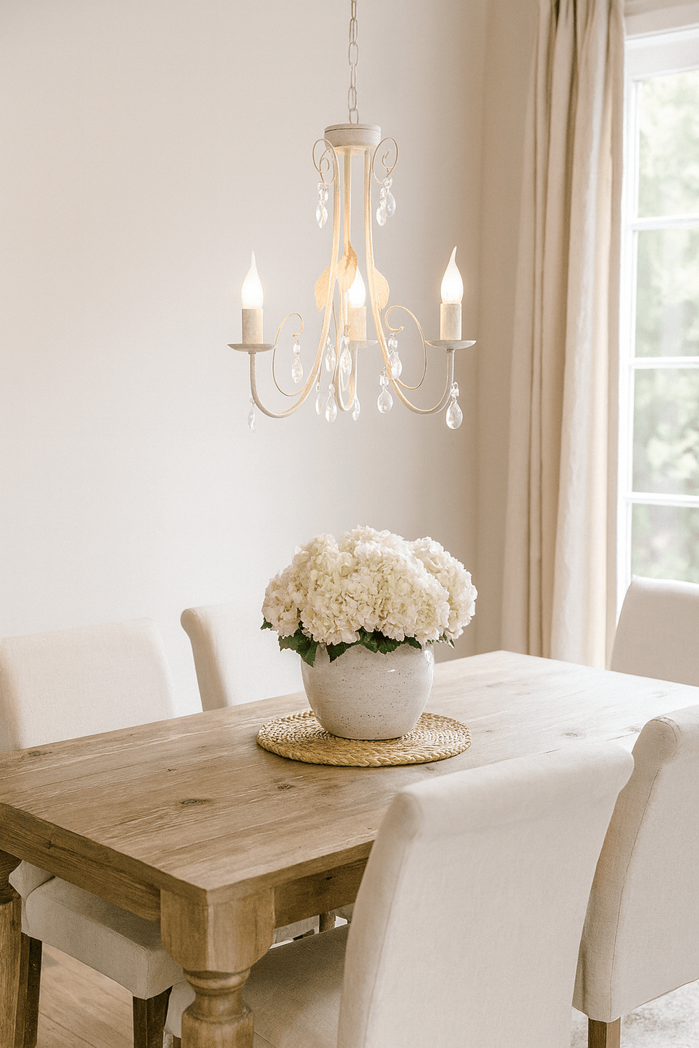 Fossil white chandelier with crystals hanging above a wooden dining table adorned with a floral centerpiece.