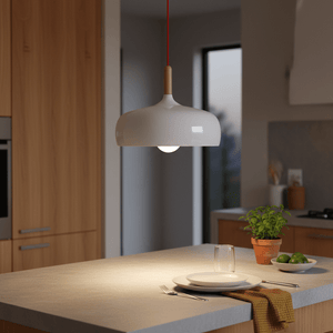 Scandinavian-style white pendant light hanging over a kitchen island with a plate and glass.