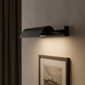 Close-up of the Goya Wall Lamp in matte black, illuminating a framed photograph on a textured wall.