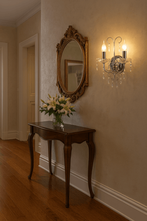 Elegant polished chrome and crystal wall light illuminating a hallway with a wooden console table and mirror.