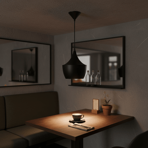 Black metal pendant light hanging above a wooden table set with a coffee cup and cutlery, creating a warm ambiance.