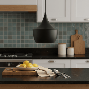 Black metal pendant light hanging above a kitchen counter with lemons and utensils.