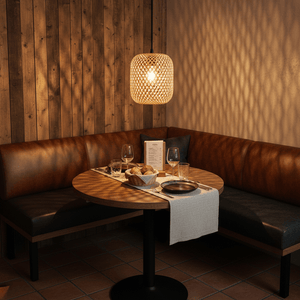 Adaya Rattan Pendant 260 hanging above a round dining table with a cozy seating area, showcasing warm light and textures.