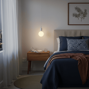 Minimalist silicone pendant light hanging above a bedside table with a book and glass of water.