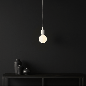 Minimalist white silicone pendant light hanging above a dark surface with black vases.