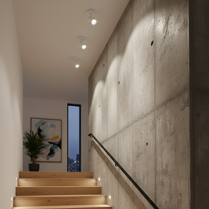 Stylish staircase illuminated by modern spotlights, highlighting a textured concrete wall and artwork.