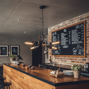 Industrial 4-light pendant hanging over a wooden bar with a chalkboard menu in the background.