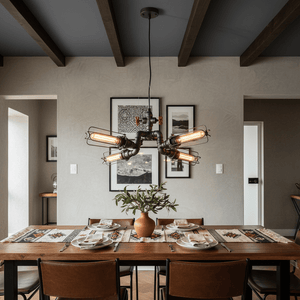 Industrial-style LED pendant light with four bulbs hanging over a wooden dining table set with plates and a vase.
