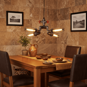 Industrial 4-light pendant hanging above a wooden dining table set with dishes and a vase.