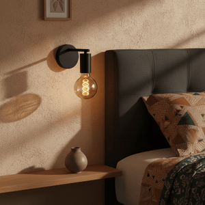 Slick Indoor Wall Lamp mounted beside a bed, casting warm light on textured wall and wooden shelf.