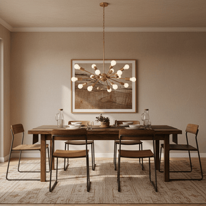 Satin gold pendant light hanging above a wooden dining table set with plates and glasses.
