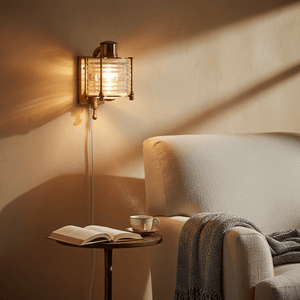 Antique brass wall lamp illuminating a cozy seating area with a book and cup on a side table.