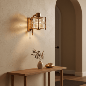 Antique brass wall lamp with handmade glass, illuminating a stylish entryway with a wooden table and decor.