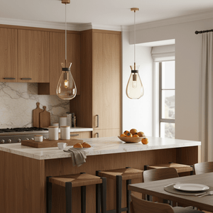 Amber Pouch Glass Pendant lights hang over a kitchen island with a marble countertop and wooden cabinets.