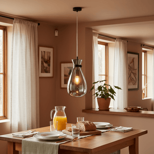 Smoke glass pendant light hanging above a dining table set with plates and drinks, creating a warm ambiance.