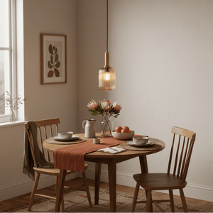Athina Amber Cut Glass Pendant hanging above a wooden dining table set with plates and a vase of flowers.
