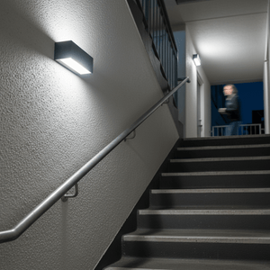 Die Cast Aluminium Bulkhead BH083 installed on a stairwell wall, illuminating steps with cool white light, enhancing safety.