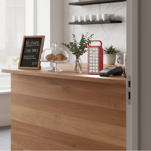 Red rechargeable LED lantern on a wooden counter beside a cash register and a glass dome with pastries.