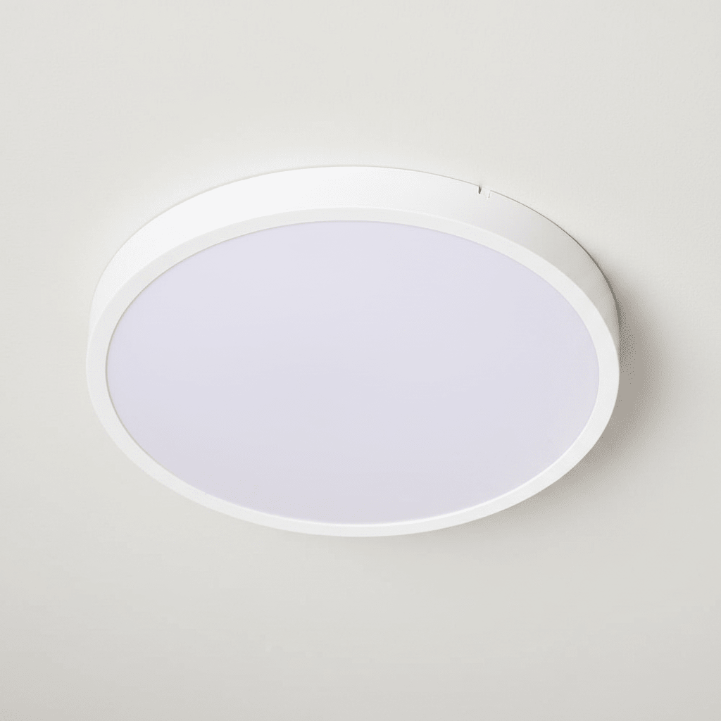 Close-up view of a round white ceiling light flush mounted on a smooth ceiling.