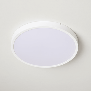 Close-up view of a round white ceiling light flush mounted on a smooth ceiling.