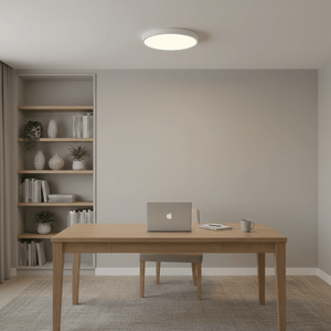 A modern workspace featuring a flush-mounted white ceiling light above a wooden desk with a laptop and coffee cup.