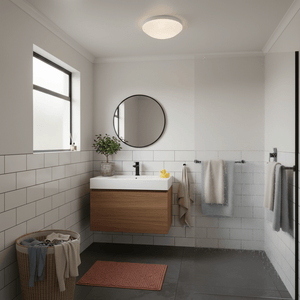 Modern bathroom featuring an alabaster ceiling light above a sleek vanity with a round mirror.