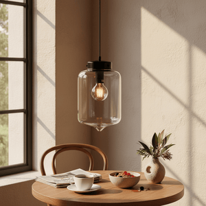A glass pendant light hangs above a wooden table with a coffee cup, newspaper, and a bowl of fruit.