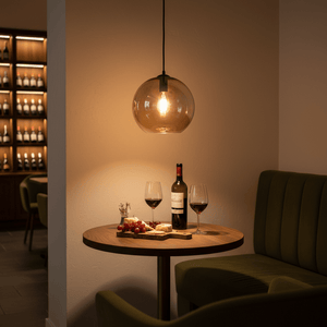 Amber glass ball pendant light with exposed bulb hanging above a table