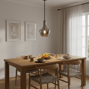Smoke glass pendant light with exposed bulb hangs over a wooden dining table set with dishes and fruit bowl.