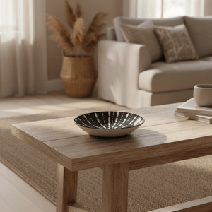 Ceramic flat bowl on a wooden table, surrounded by a cozy living room setting with a sofa and decorative elements.