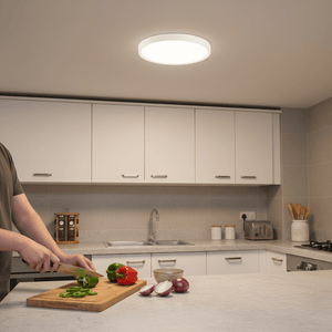 A person chopping vegetables on a kitchen countertop under a round white ceiling light.