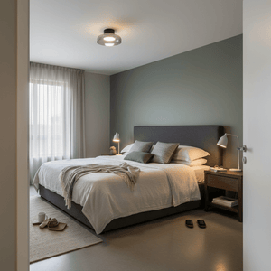 Modern bedroom featuring a smoke glass metal ceiling light above a neatly made bed with decorative pillows.
