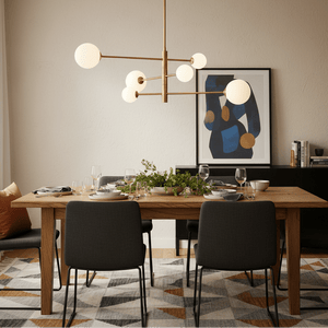 Stylish dining setup featuring a gold pendant light above a wooden table with plates and glasses.