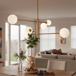 Gold pendant light with six spherical shades hanging above a dining table with apples and a vase.