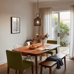 Chestnut Glass Pendant light hanging above a wooden dining table with green chairs and a floral centerpiece.