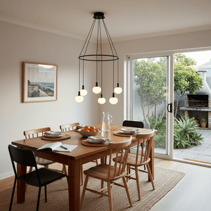 Modern 6-light chandelier with opal glass orbs hanging above a wooden dining table set for a meal.
