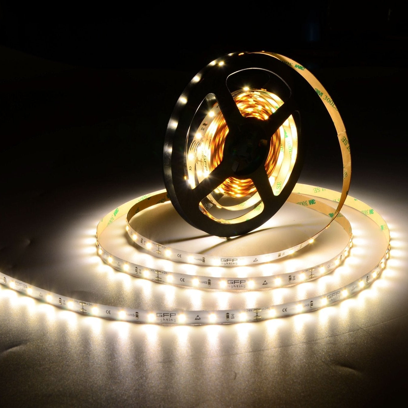 Close-up of a 24V LED strip light roll with illuminated sections, showcasing its flexible design.