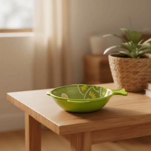 Ceramic fish-shaped bowl with green and yellow dot scales on a wooden table, with a plant in the background.