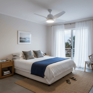 Modern bedroom featuring a white ceiling fan with light, cozy decor, and natural light from a balcony.