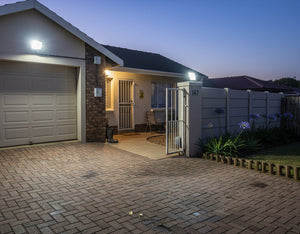 LED flood light twin pack illuminating a driveway and entrance at dusk, showcasing bright, reliable lighting.