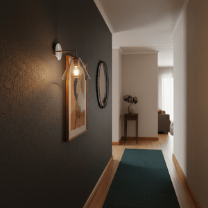 Satin chrome wall light illuminating a dark hallway with artwork and a mirror.