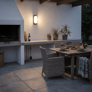 Outdoor patio with a Fumagalli Francy Bulkhead Light illuminating a dining area with wicker chairs and a wooden table.
