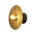 Decorative wall light with textured gold shade on a black background