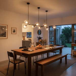 A modern dining area featuring a long wooden table with a black 8-light pendant above, surrounded by chairs and decor.